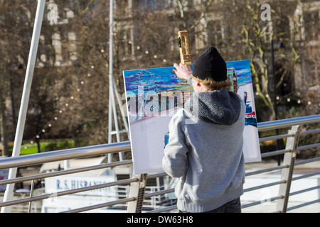 LONDON, UK - 16TH FEB 2014: An artist on a bridge in central London painting popular landmarks. Stock Photo