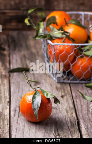 Tangerines with leaves on old wooden background. See series Stock Photo