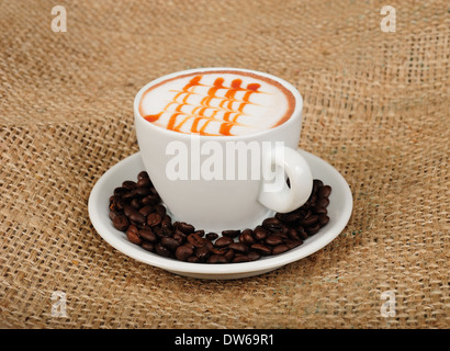 Cappuccino with coffee beans on jute background Stock Photo
