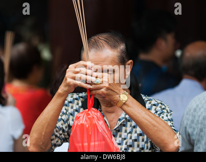 Buddhists pray and burn incense at Kwan Im Thong Hood Cho Temple in Singapore. Stock Photo