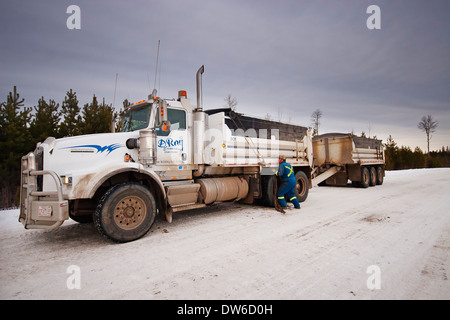 A Canadian truck driver putting chains on the tyres in snowy weather Stock Photo