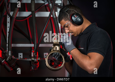 An operator taking a close look at a spare in front of his shot blasting machine. Opérateur examinant une pièce mécanique. Stock Photo