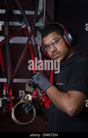 An operator taking a close look at a spare in front of his shot blasting machine. Opérateur examinant une pièce mécanique. Stock Photo