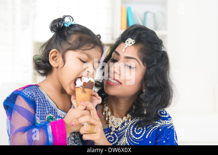 Eating ice-cream. Happy Asian India family sharing ice-cream at home. Beautiful Indian child licking ice-cream cone. Stock Photo