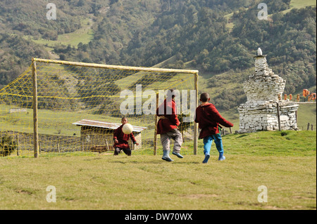 Boys wearing traditional clothes play football in school playground, village of Sakteng on Merak Sakteng trek, Eastern Bhutan Stock Photo