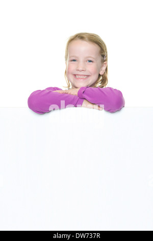 Smiling young girl with blank sign in front of white background Stock Photo