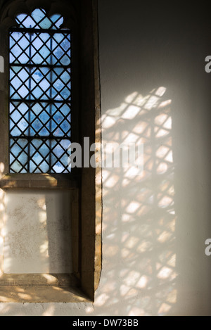Diamond leaded windows in a church with sunlight and shadows. UK Stock Photo