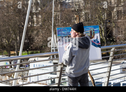LONDON, UK - 16TH FEB 2014: An artist on a bridge in central London painting popular landmarks. Stock Photo