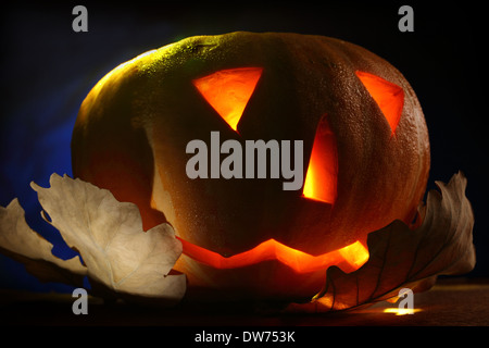 Halloween pumpkin on leaves at night Stock Photo