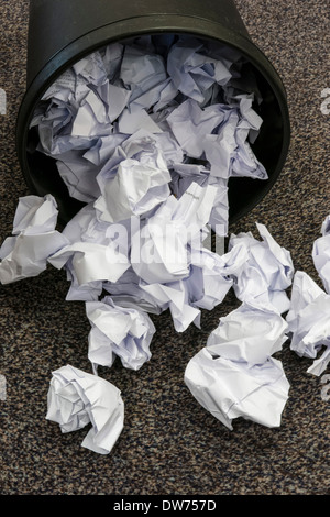 Full waste paper bin on its side with paper spilled on to floor Stock Photo