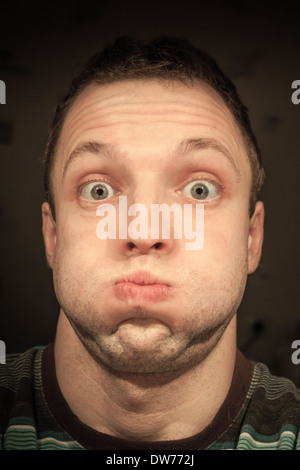 Young funny Caucasian man inflates cheeks. Closeup portrait Stock Photo