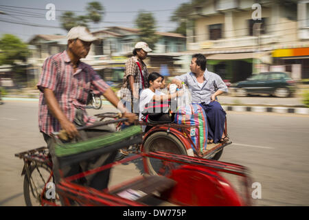 March 2, 2014 - Myawaddy, Kayin, Myanmar - A pedicab driver takes a family into Myawaddy, Myanmar. Pedicabs are still used in much of Myanmar (Burma). Myawaddy is separated from the Thai border town of Mae Sot by the Moei River. Myawaddy is the most important trading point between Myanmar and Thailand. (Credit Image: © Jack Kurtz/ZUMAPRESS.com) Stock Photo