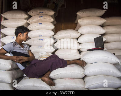 March 2, 2014 - Myawaddy, Kayin, Myanmar - A rice sellers watches a movie on his laptop in the main market in Mywaddy, Myanmar. Myawaddy is separated from the Thai border town of Mae Sot by the Moei River. Myawaddy is the most important trading point between Myanmar (Burma) and Thailand. (Credit Image: © Jack Kurtz/ZUMAPRESS.com) Stock Photo