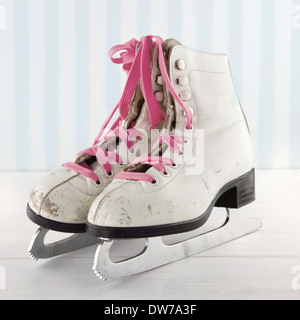 Pair of white women's ice skates on white and blue vintage background with pink shoe laces Stock Photo