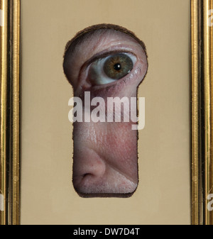 Close up of human eye looking through a keyhole Stock Photo