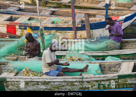 Fishermen mending fishing nets in Elmina Harbour, Elmina, Cape Cost, Ghana Stock Photo