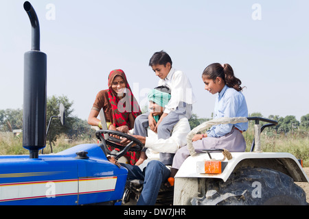 Indian farmer driving tractor with his family Stock Photo