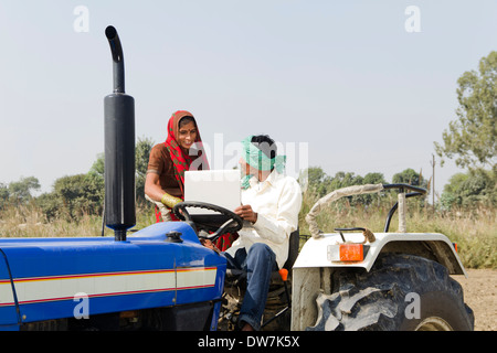 Farmer driving a tractor with his wife sitting beside him Stock Photo ...