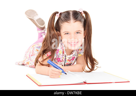 Little girl laying on the floor and drawing pictures in a notebook Stock Photo