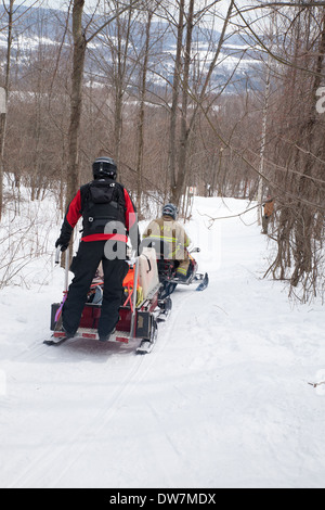 Members of the Thunderbolt Ski Patrol ride a snowmobile and pull sled after the Annual Thunderbolt Ski Run in Adams MA. Stock Photo