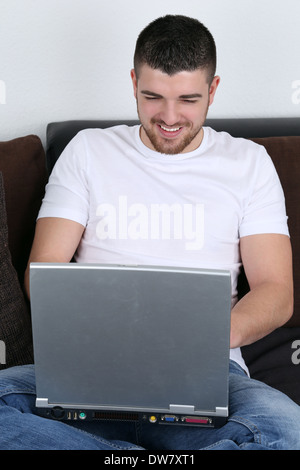 A young man is using his laptop computer on a sofa Stock Photo