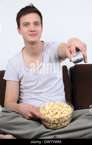 A young man is sitting on a sofa and watching tv Stock Photo