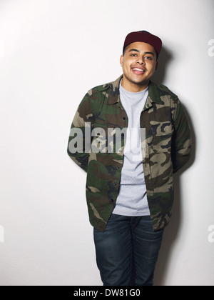 Portrait of happy young guy wearing camouflage jacket. Hispanic male model posing against white background Stock Photo