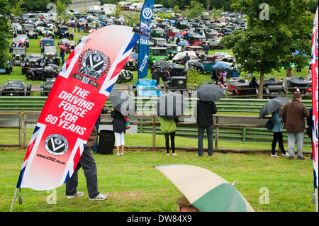 Spectators sheltering from the rain under umbrellas at the VSCC Prescott Speed Hill Climb, Gloucestershire, England, UK. Stock Photo