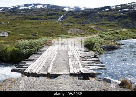 A Plank Bridge in the Mountains Leading over a small River Stock Photo