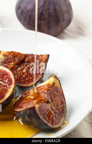 White plate with sliced figs and flowing honey Stock Photo