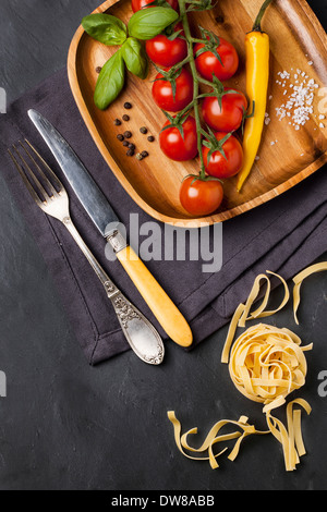 Tomatoes on the vine, basil and yellow chili served on wooden dish Stock Photo