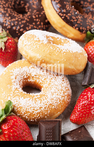 Close up of sugar donuts, fresh strawberries and dark chocolate over grey textile Stock Photo