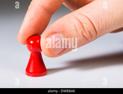 Hand holding red pawn on white background. Close up Stock Photo