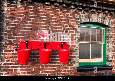 Red fire buckets on the platform at Sheringham Station in North Norfolk. Stock Photo