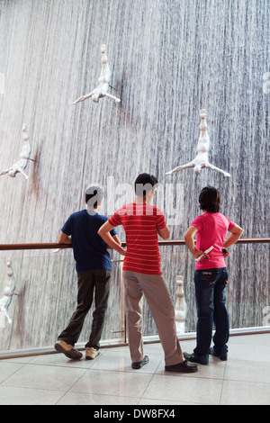 Three local teens teenage boys looking at the Waterfall in the Dubai Mall, Dubai, UAE, United Arab Emirates Middle East Stock Photo