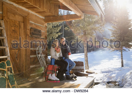 Couple sitting on cabin porch in winter