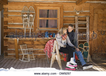 Couple sitting on cabin porch wearing ice skates