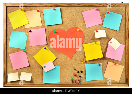 Blank colorful paper notes , office supplies and red paper heart on cork message board. Stock Photo