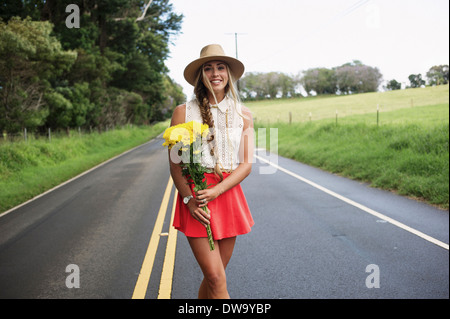 Young woman with flowers on road Stock Photo