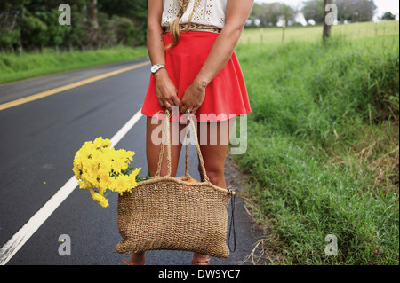 Woman with straw bag on roadside Stock Photo