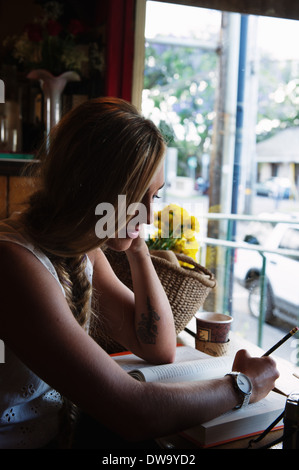 Young woman writing on book in cafe Stock Photo