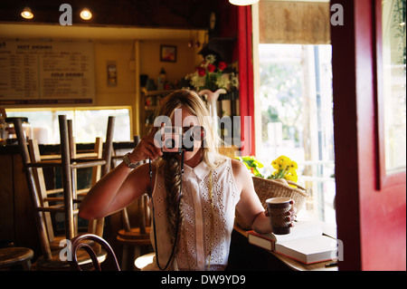 Young woman taking photograph in cafe Stock Photo