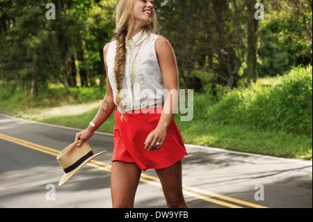 Young woman with hat crossing road Stock Photo