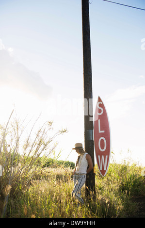 Young woman leaning on sign post Stock Photo