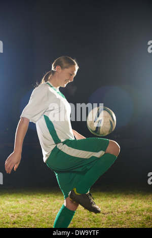 Female soccer player bouncing ball on knee Stock Photo