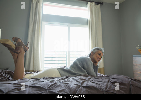 Mature woman relaxing on luxury bed Stock Photo