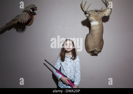 Home portrait of girl holding pink shotgun Stock Photo