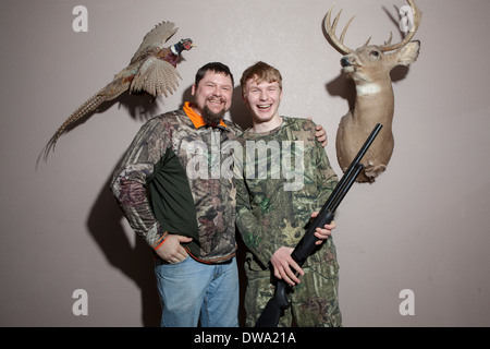 Home portrait of father and teenage son holding shotgun Stock Photo