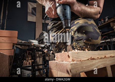 Close up of male carpenter drilling wooden plank in workshop Stock Photo