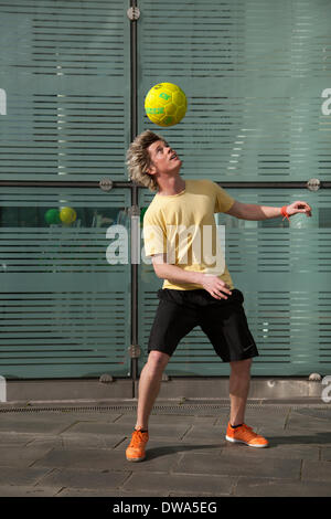 Manchester UK. European Freestyle Soccer Champion John Farnworth, MR, showing his football 'Keepy Uppy' skills, tricks, fun, lifestyle, fitness, happy, practice, recreation, talented , exercise, game, kicking football, a Pelé-inspired freestyle performance, in the streets near the Urbis National Football Museum.  World Cup 100 Day Countdown Carnival a day of celebrations as Mardi Gras to celebrate the beginning of the 100 day countdown to this year’s World Cup!  John is a football freestyler and entertainer who holds four Guinness World Records including the most around the worlds in a minute. Stock Photo